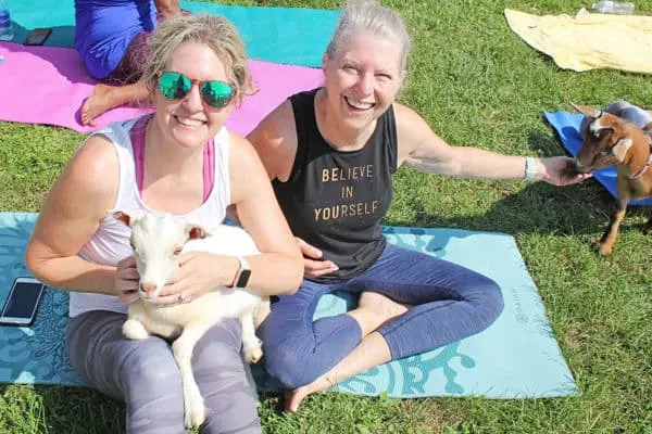 two women holding goat at yoga