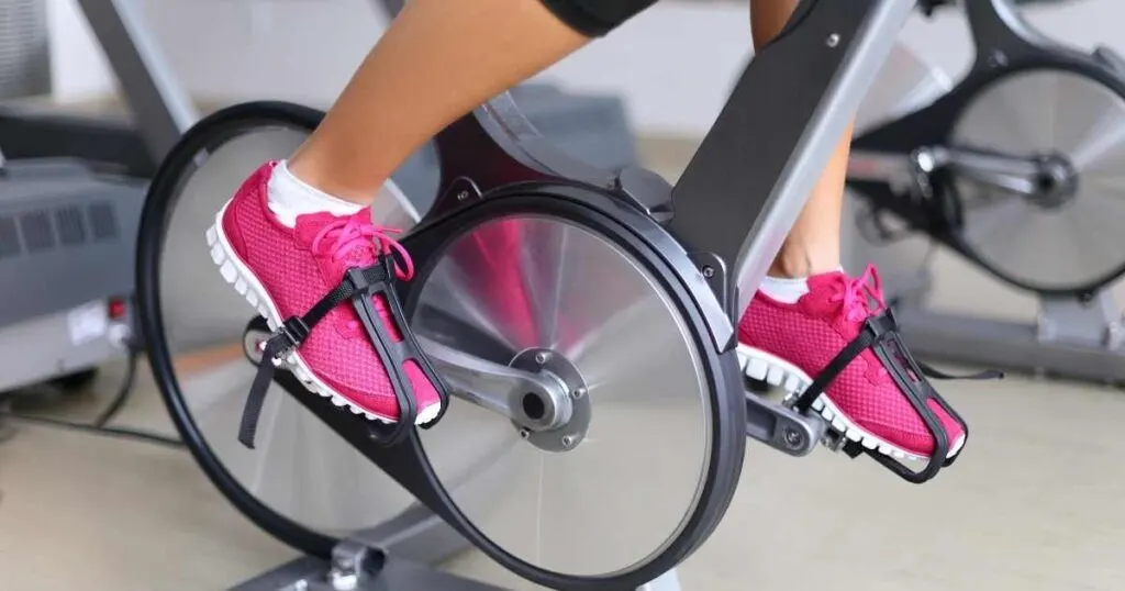 woman using spin bike poor positioning feet pointed downward