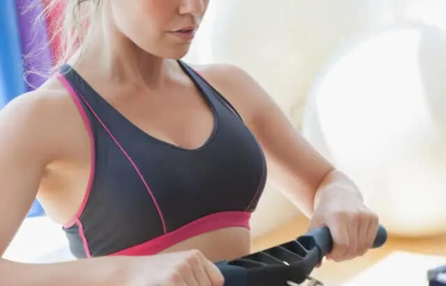 Woman pulling on row machine in fitness studio
