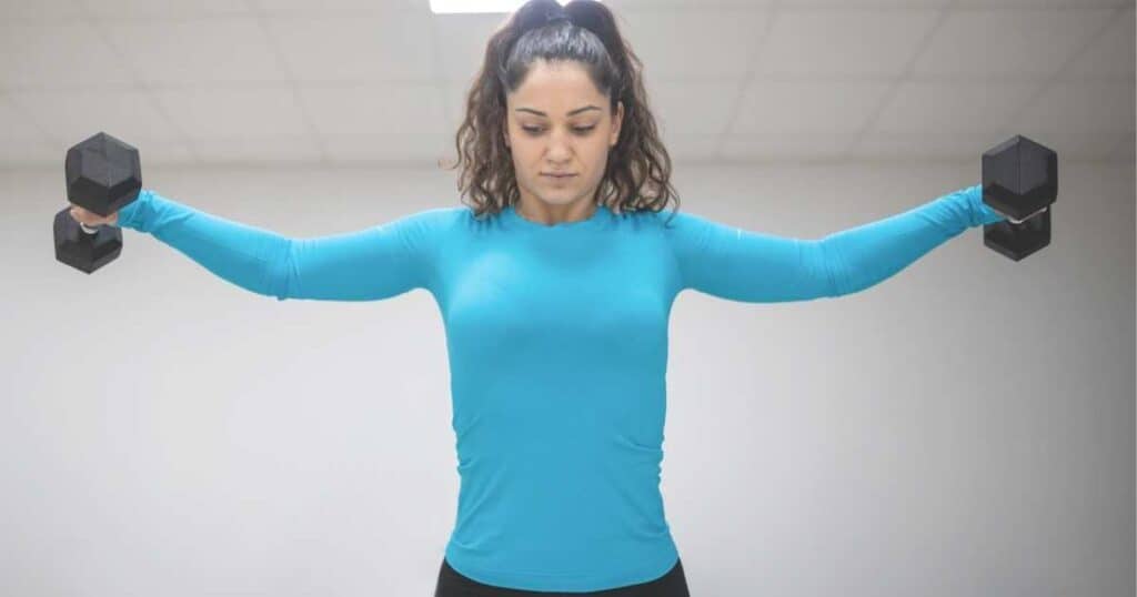 woman doing lateral raises with dumbbells