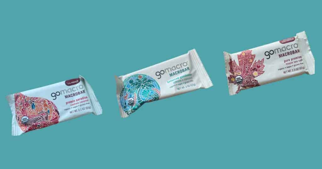 three flavors of gomacro protein bars blue background