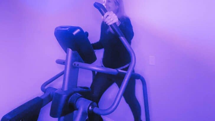 purple lighting woman on elliptical machine