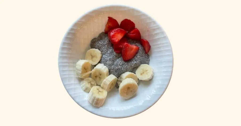 chia pudding in a white bowl with bananas and strawberries