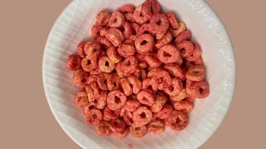 White bowl of fruity flavor three wishes cereal, pink background