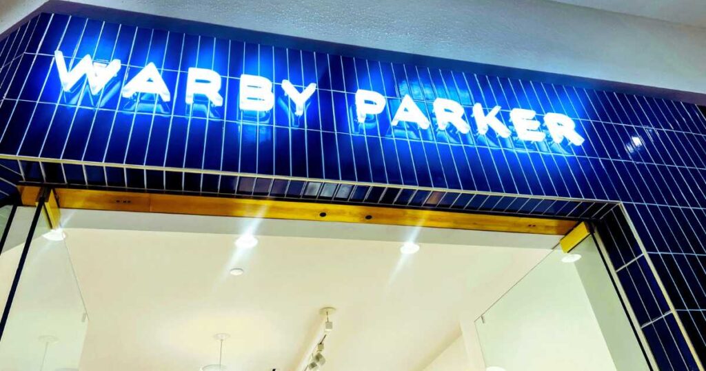 lit up warby parker sign on storefront