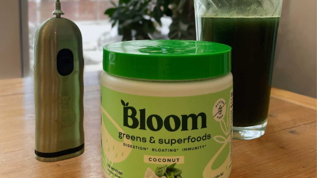 bloom greens container next to glass and coffee frother