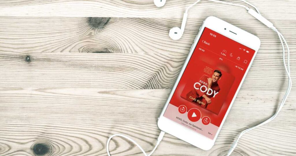 iphone showing red cover of cody rigsby''s audiobook with headphones