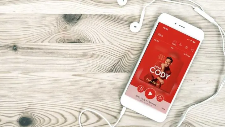 iphone and earbuds on wood floor showing peloton instructor cody rigsby's audiobook red cover image of cody