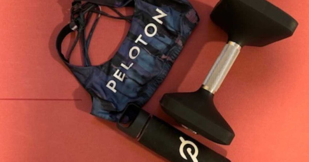 Peloton water bottle dumbbell and sports bra on red mat