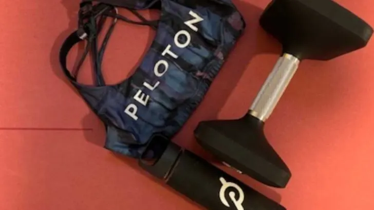 Peloton water bottle dumbbell and sports bra on red mat