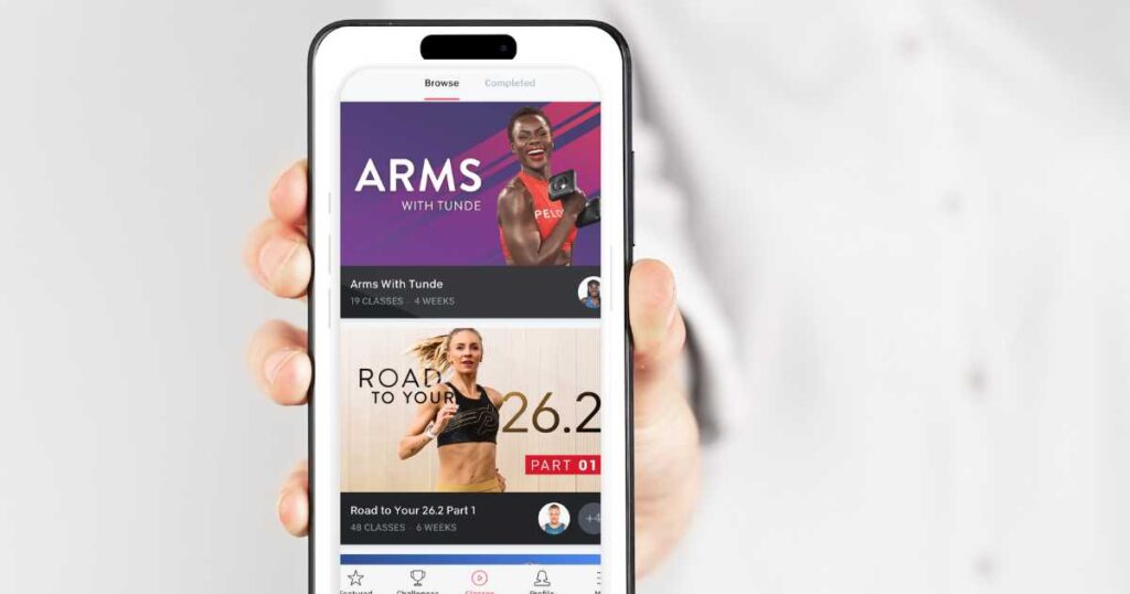 hand holding iphone showing peloton programs arms with tunde and marathon training