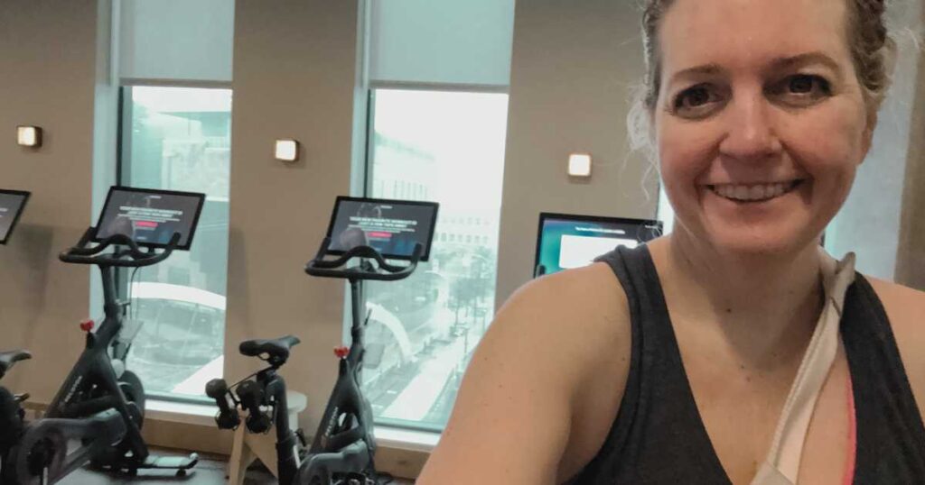 Michelle Platt smiling in front of Peloton bikes at Proper Hotel in Austin Texas gym