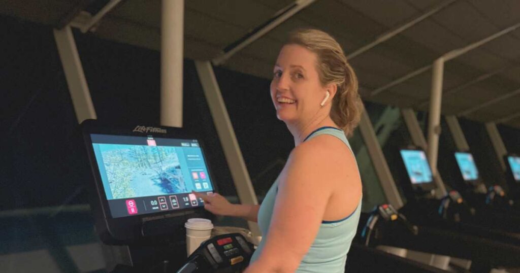 woman using life fitness treadmill on royal caribbean freedom of the seas smiling at camera with airpods in