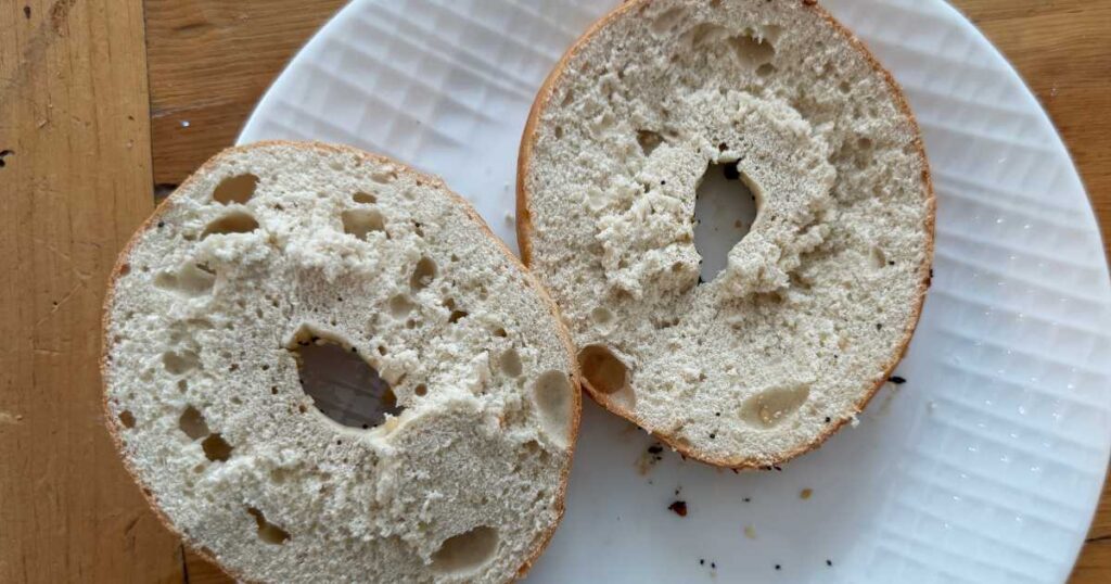 sliced better bagel on a white plate not toasted.