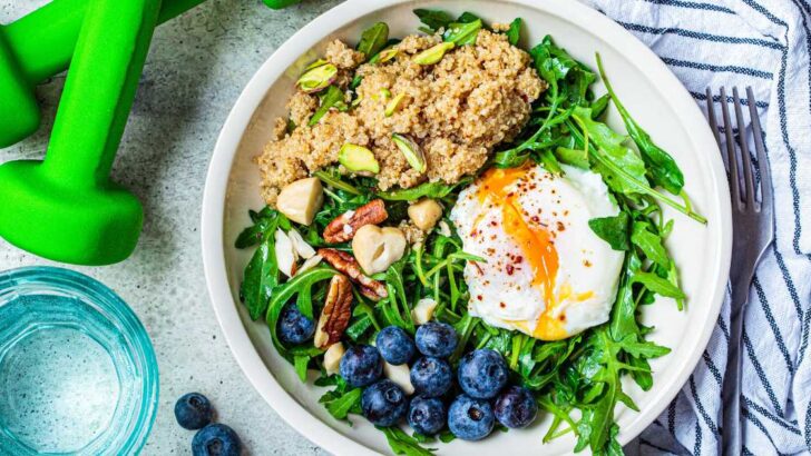 plate of healthy grains, protein, and vegetables next to dumbbells