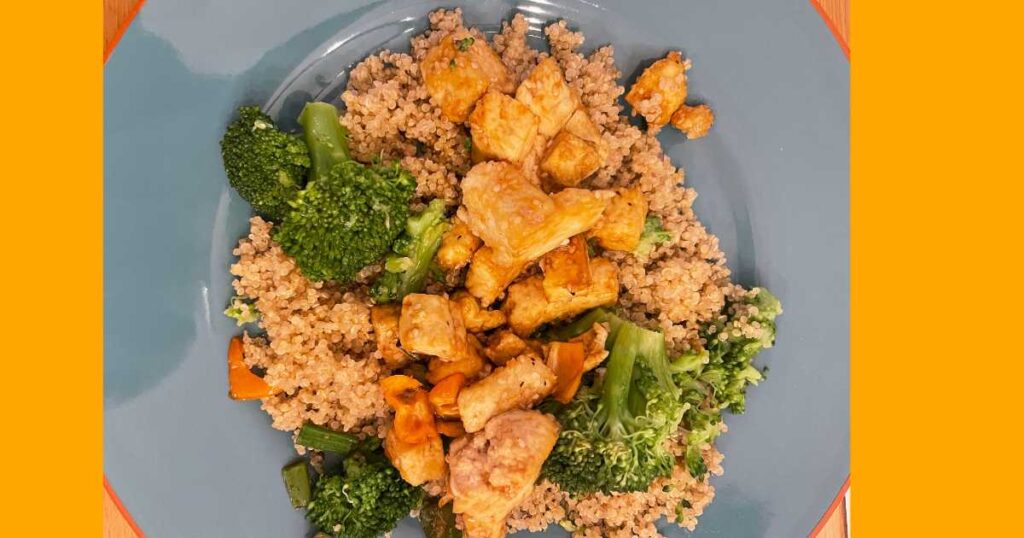 quinoa on a blue plate with brocooli and tofu orange background