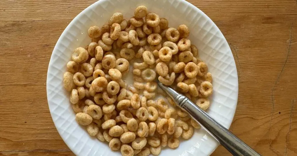 peanut butter magic spoon cereal in a white bowl with a spoon on a wooden table.