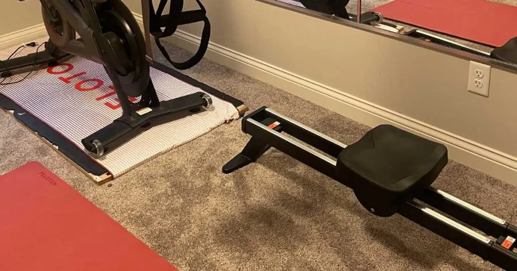 Peloton bike next to rowing machine on carpet. 