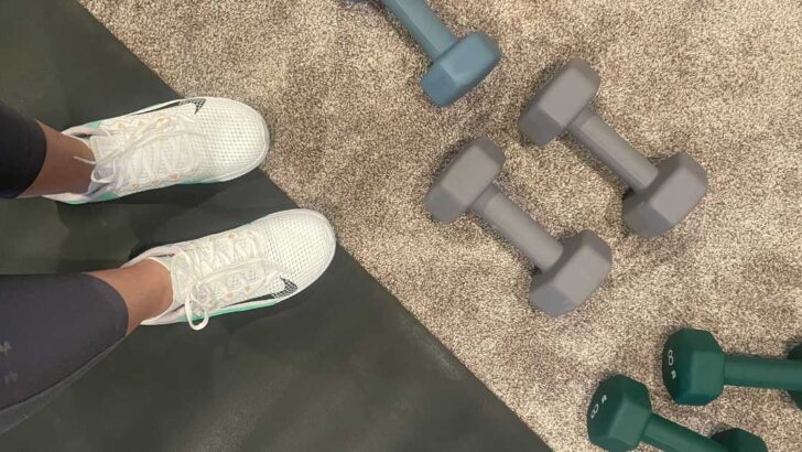 dumbbells on a carpet next to an exercise mat and shoes