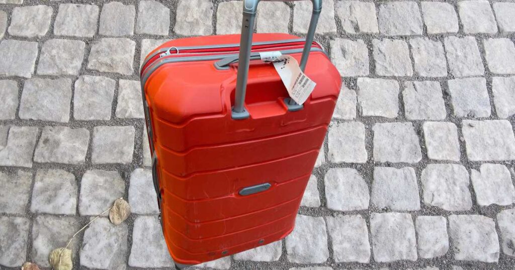 orange suitcase on a cobblestone street.