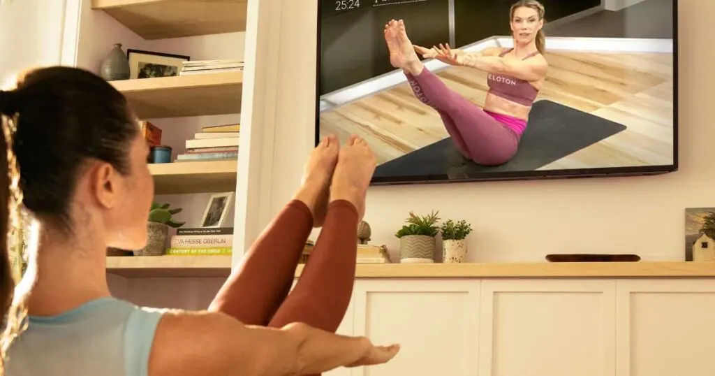 woman doing pilates in front of tv screen with peloton instructor kristin mcgee.