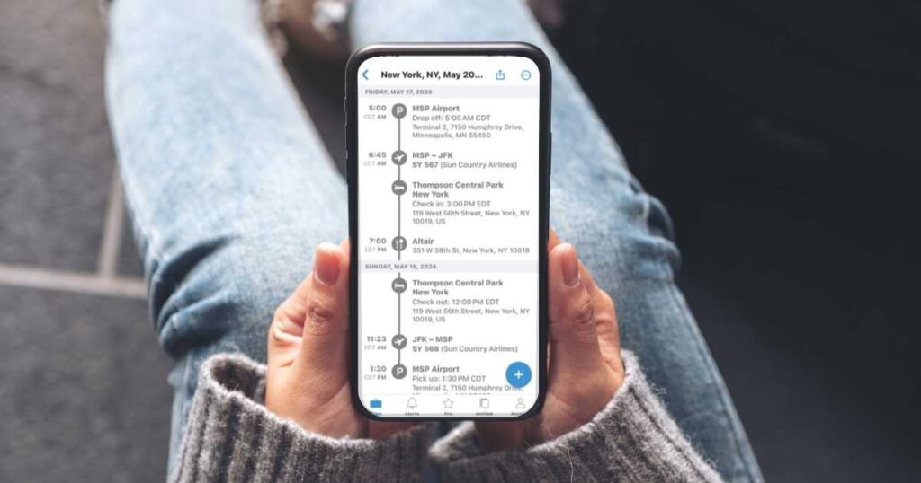 woman holding an iphone on her lap wearing jeans looking at a tripit itinerary on her phone. 
