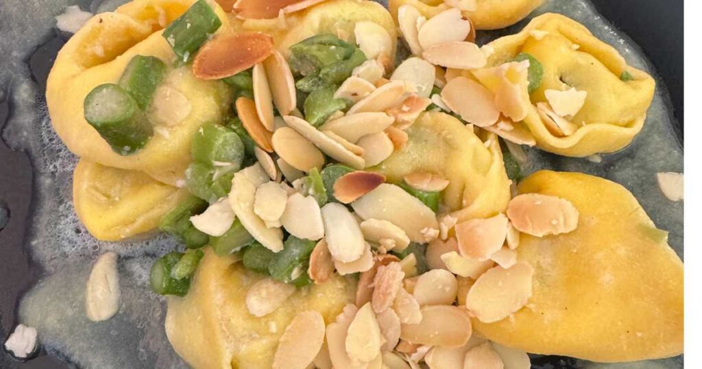 close up tortellini pasta with asparagus and almonds.