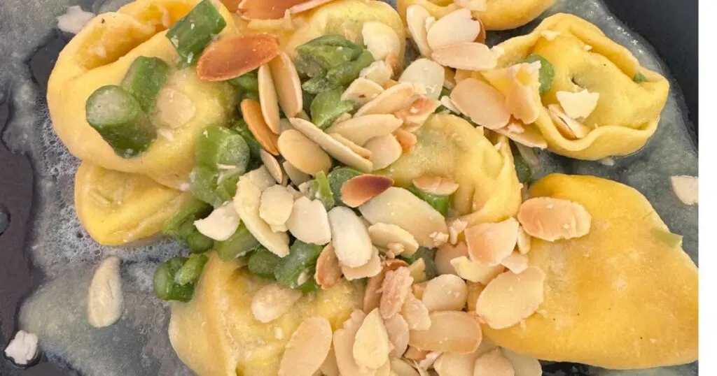 close up tortellini pasta with asparagus and almonds.