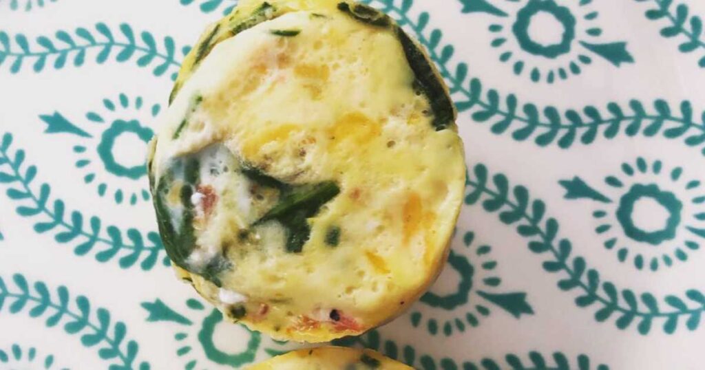 egg muffin pan bites with vegetables on blue and white plate.