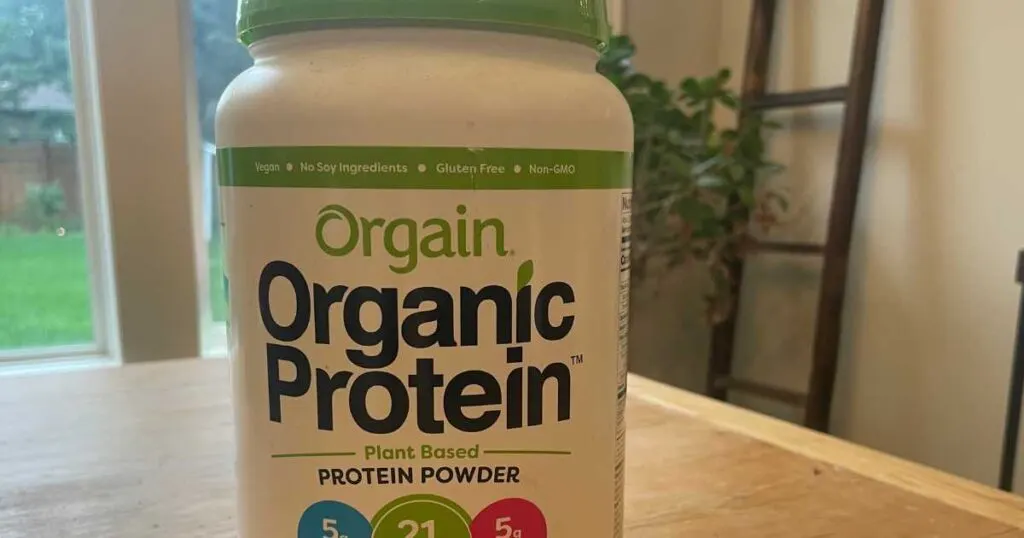 Container of Organic Orgain Protein Powder on wood table.