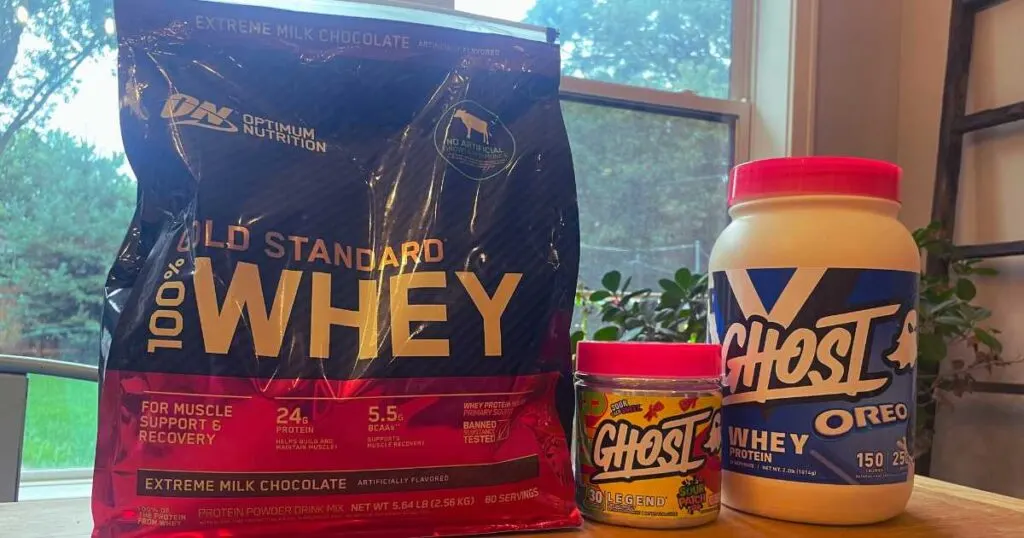 Optimum Nutrition whey protein bag next to containers of Ghost Whey Protein.