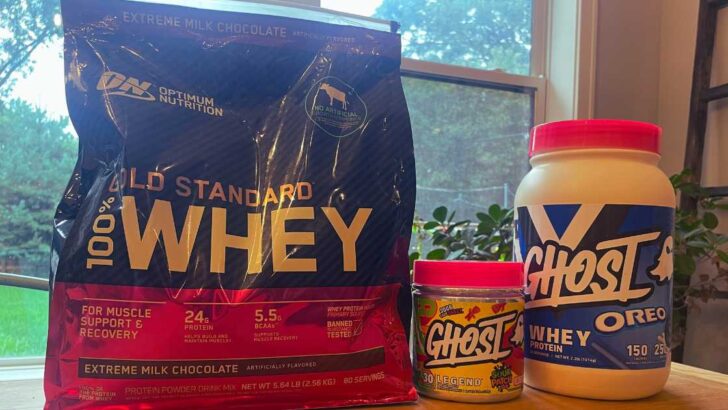 Optimum Nutrition whey protein bag next to containers of Ghost Whey Protein.