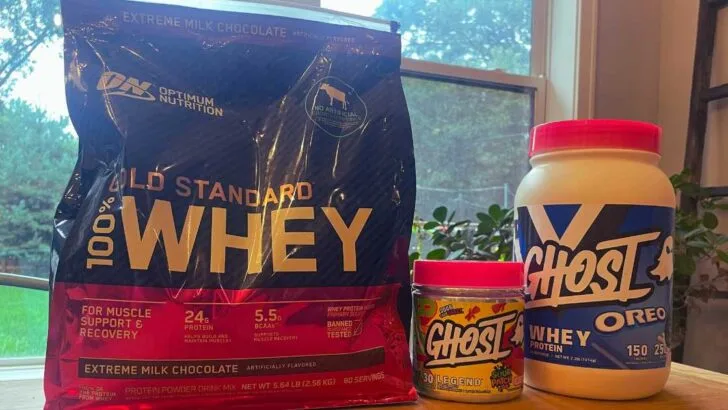 Optimum Nutrition whey protein bag next to containers of Ghost Whey Protein.