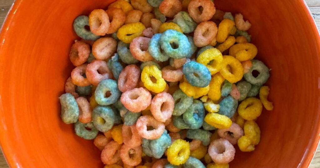 orange ceramic bowl filled with colorful Os of Magic Spoon protein cereal.