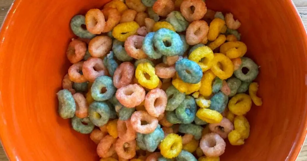 orange ceramic bowl filled with colorful Os of Magic Spoon protein cereal.