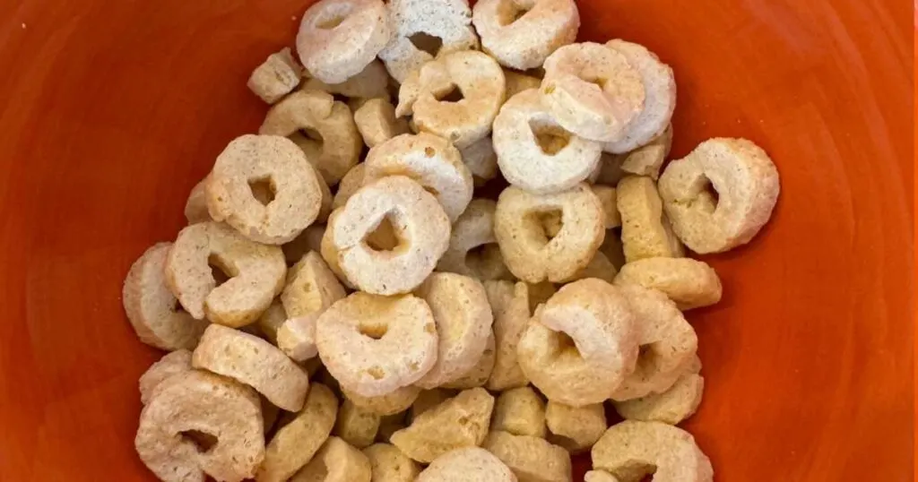 Orange background Three WIshes cereal Os in bowl.
